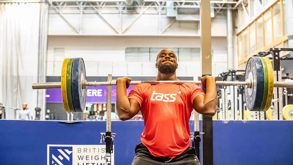 A man lifting a barbell with weights on in a gym